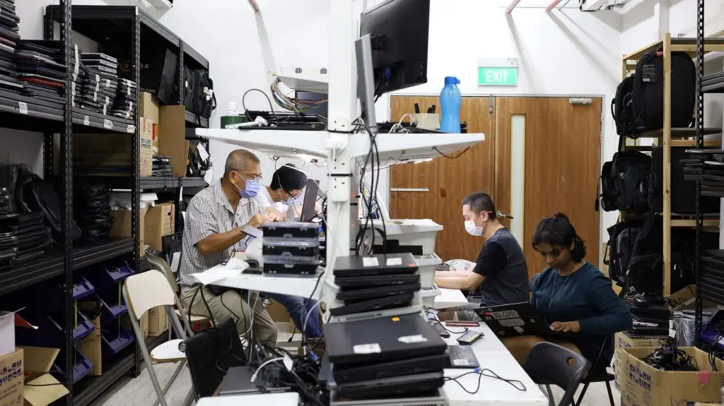 Volunteers repairing donated laptops