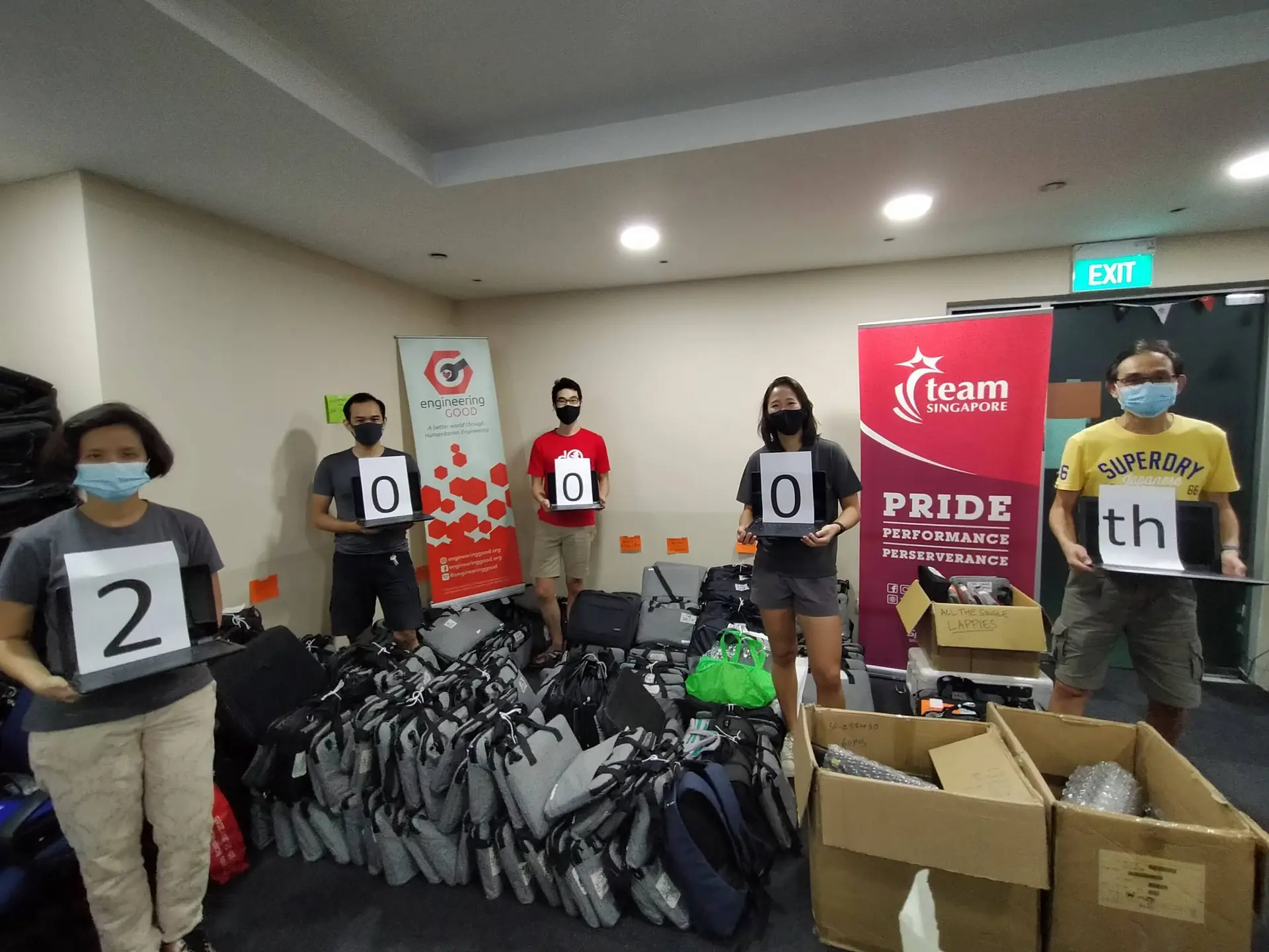 Volunteers holding laptop donations by Engineering Good. EG is a tech and engineering charity in Singapore, empowering vulnerable and low-income communities.